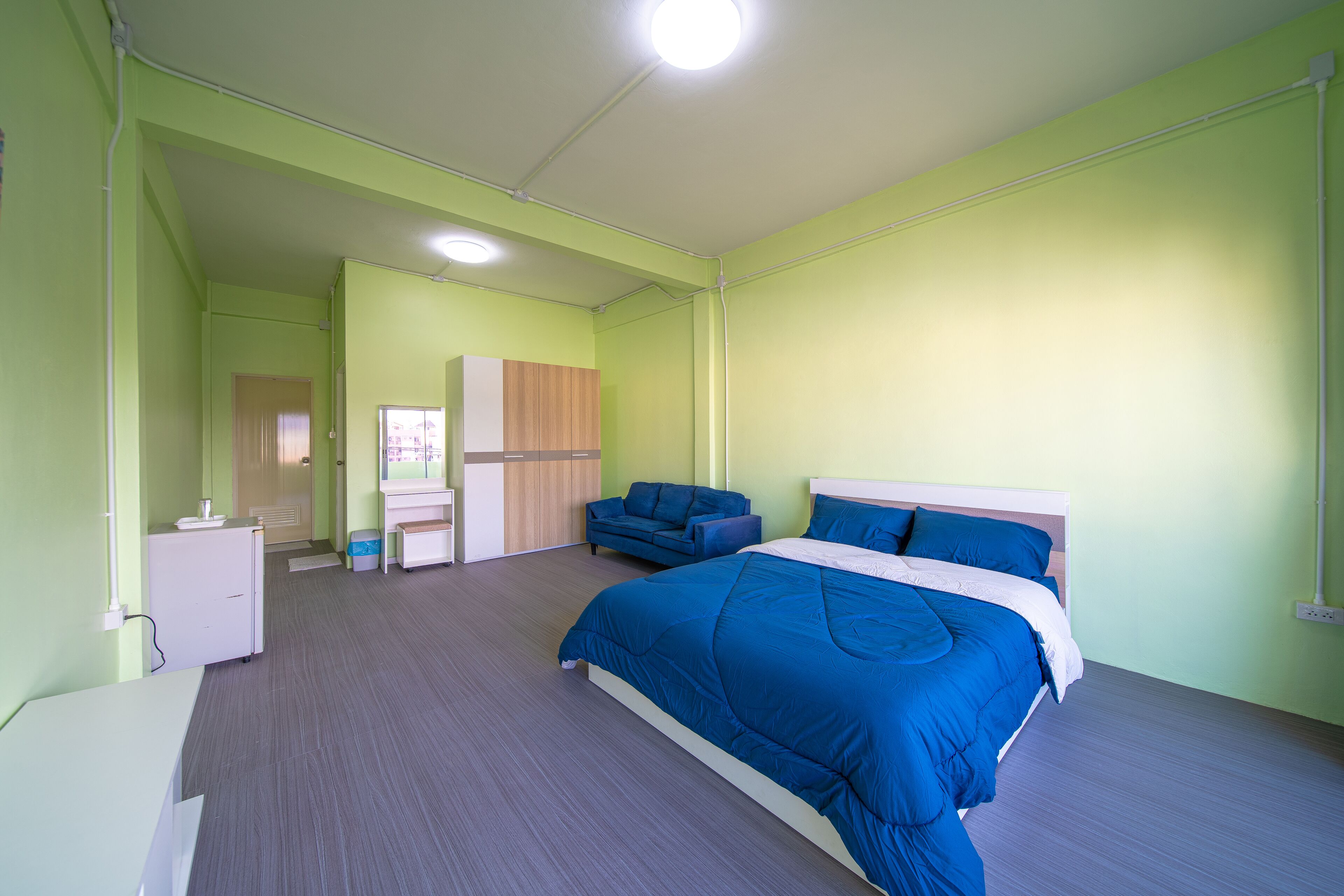 A bedroom with a bed, a desk, a wardrobe, and a sofa.