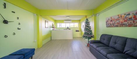 A bright room with a reception desk, a blue bench, a black sofa, and a small Christmas tree.