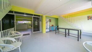 A bright, modern interior with a staircase, white wicker chairs, and a kitchen area. - UrbanNest Hostel  (Pattaya)