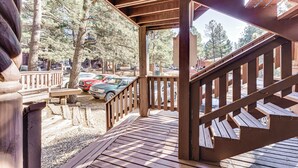 A wooden deck with a staircase leading to a covered area, surrounded by trees and parked cars. - Walk to Angel Fire Resort: Condo w/ Furnished Deck (Angel Fire)