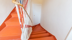 Una escalera con escalones anaranjados y barandillas blancas.
