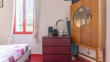 Une chambre à coucher avec un lit, une commode, un miroir et une fenêtre avec des rideaux.
