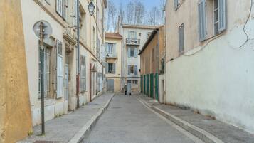 A narrow street with buildings on either side, a person walking down the street, and a clear sky.