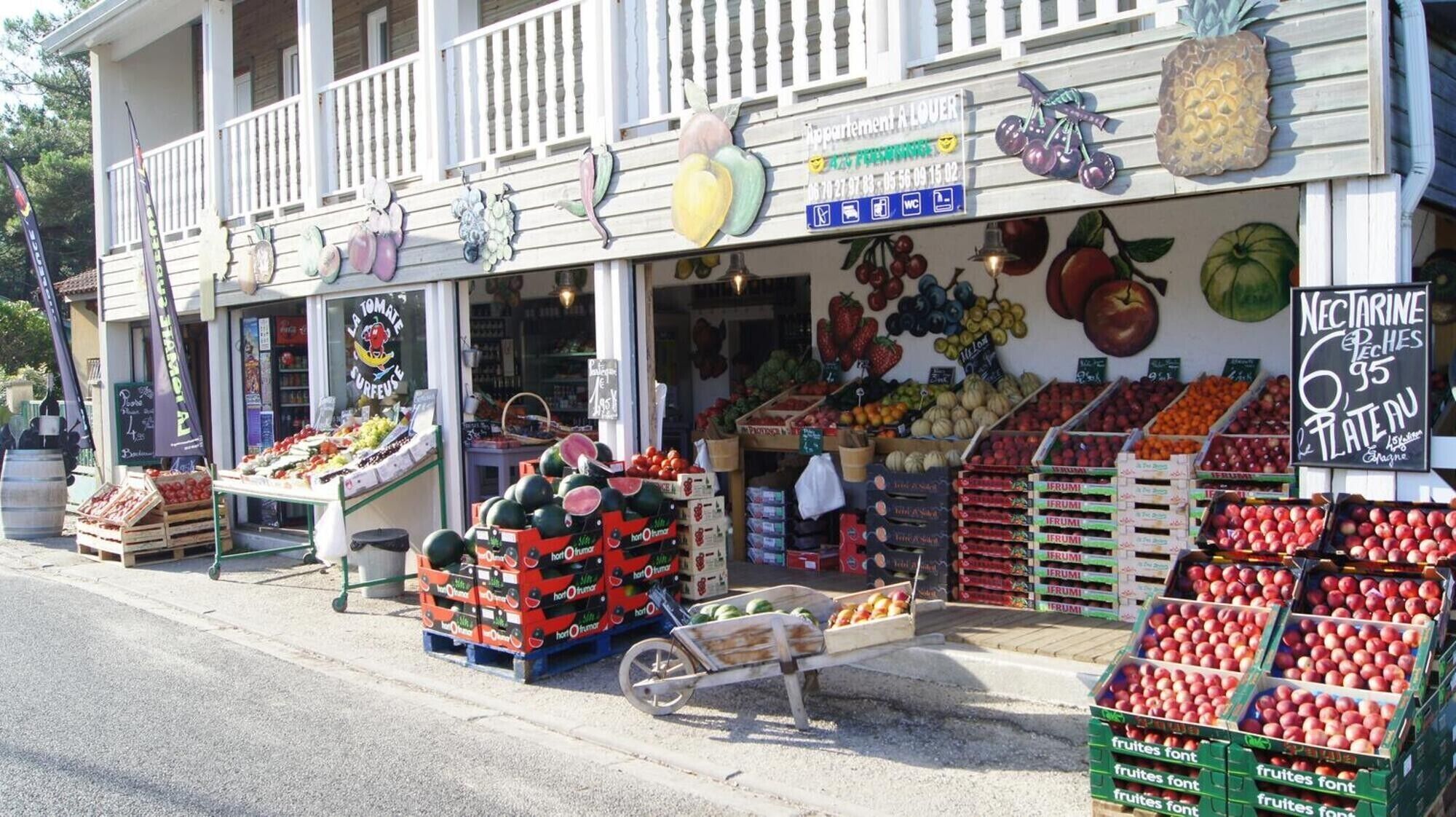 Un étal de fruits et légumes, avec une variété de produits exposés à l’extérieur d’un bâtiment.