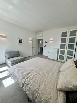 Relax in this serene bedroom with a large bed, sofa, and ample storage in the spacious wardrobe.
