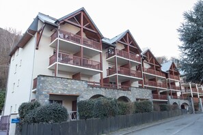 Un hôtel à plusieurs étages doté de balcons, d’une façade en pierre et d’une clôture en bois.