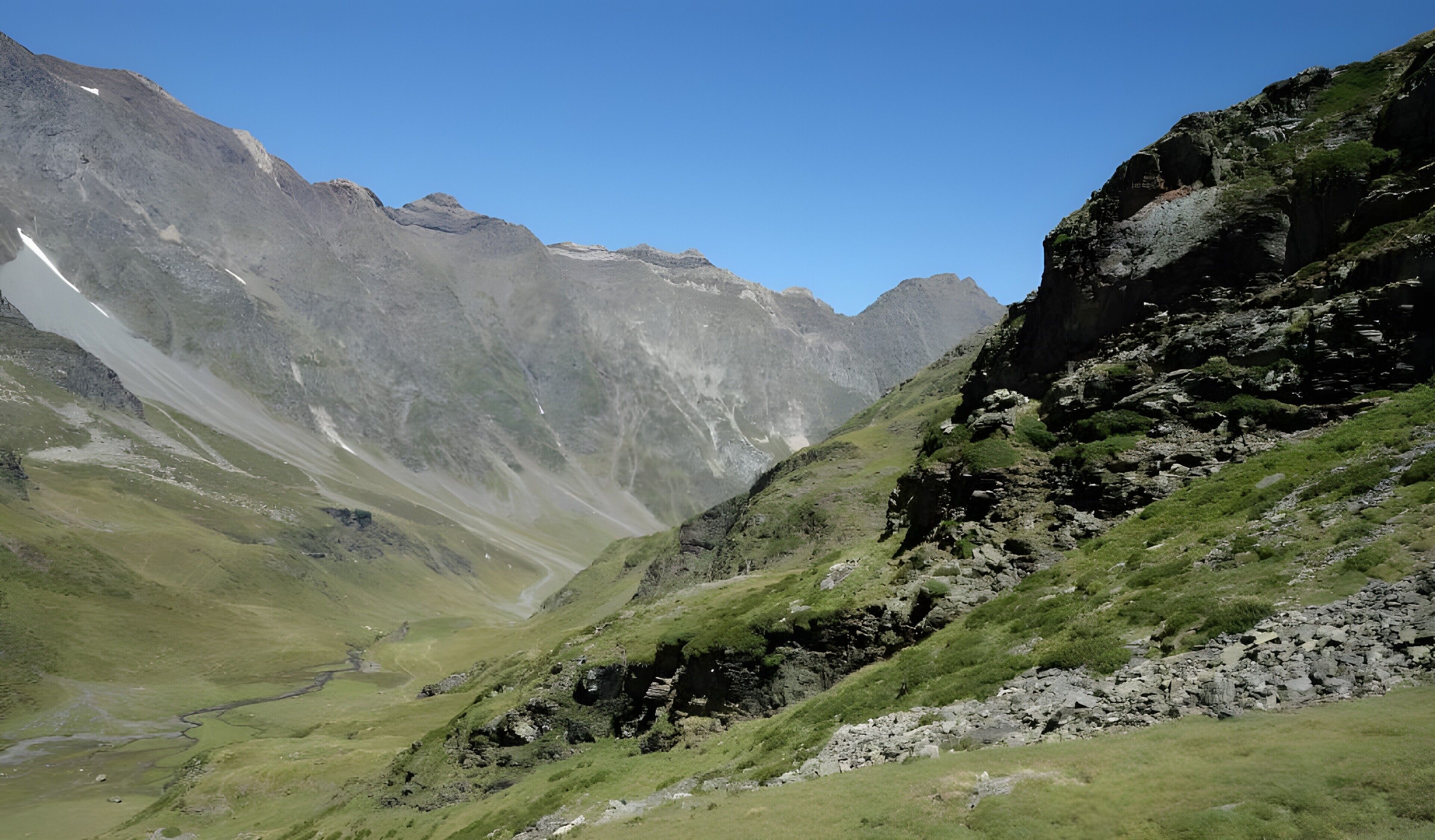Un paysage montagneux comprenant une vallée, un terrain rocheux et un petit cours d’eau.