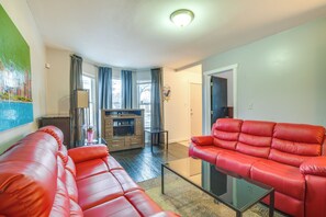 Una sala de estar con sofás de cuero rojo, una mesa de centro de vidrio y un aparador de madera.