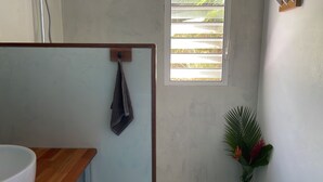 A bathroom with a towel hanging on a rack, a window with blinds, and a potted plant. - Charming T1 50 m from Anse Bonneville beach, beach and idleness guaranteed! (La Trinité)