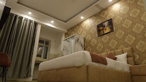 A bedroom with a bed, a wardrobe, and a painting on the wall. - The Sandalwood By La Carnation (Sohna)