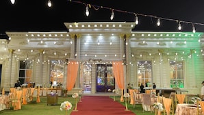 A grand building with a red carpet leading to a large entrance, adorned with string lights and draped curtains. - The Sandalwood By La Carnation (Sohna)