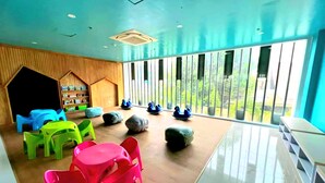 Una habitación con ventanas amplias, paredes de madera y muebles de plástico de colores.