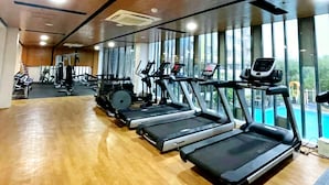 Un gimnasio con cintas de correr, bicicletas estáticas y máquinas de pesas.