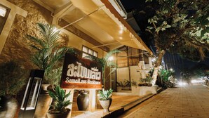 A hotel entrance with a signboard, potted plants, and a paved pathway. - Samailaos Residence (Luang Prabang)