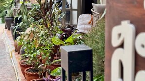 A patio area with potted plants, a wooden sign, and a covered seating area. - Samailaos Residence (Luang Prabang)