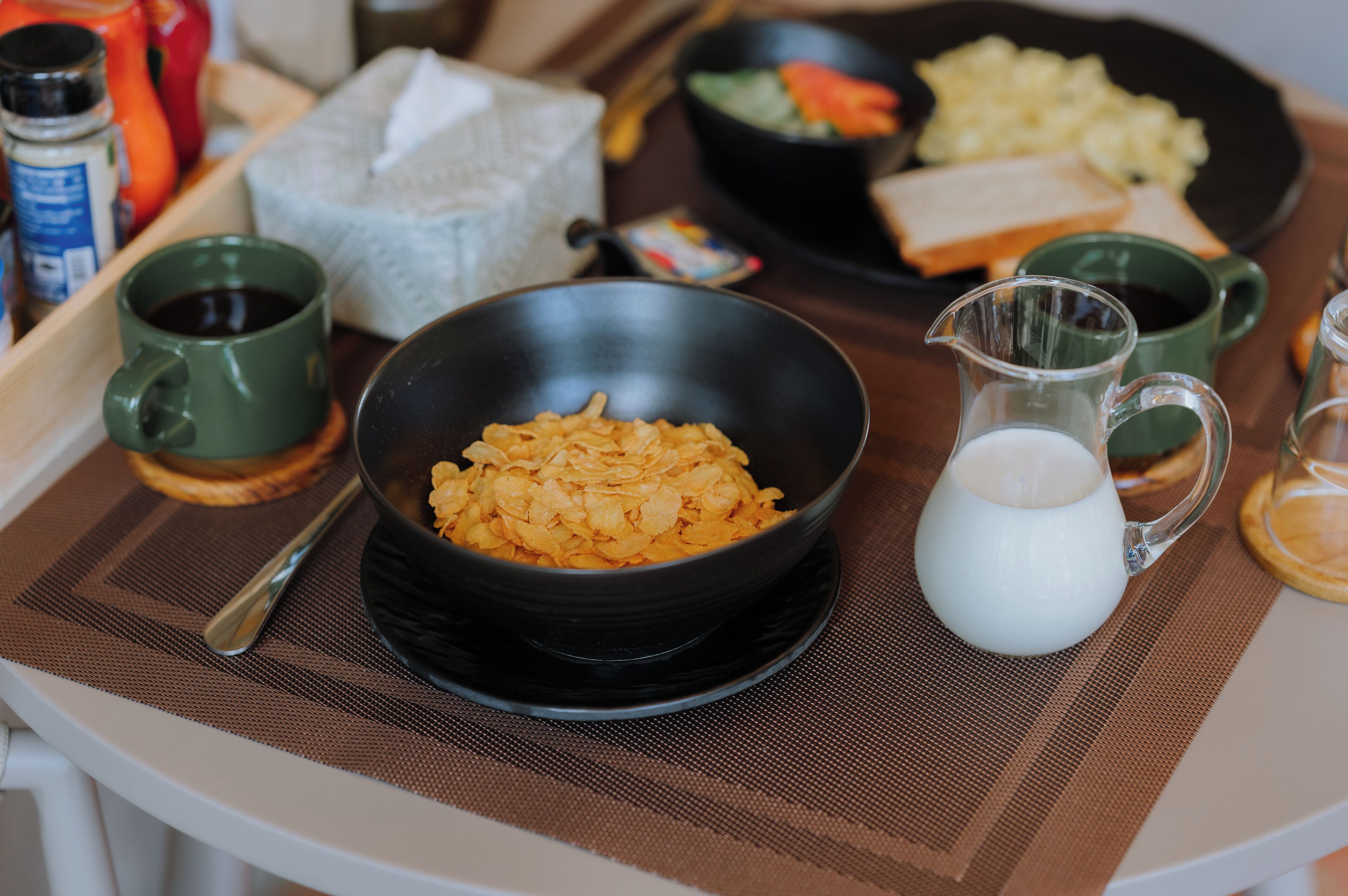 A breakfast tray with cereal, milk, and a pitcher of milk.