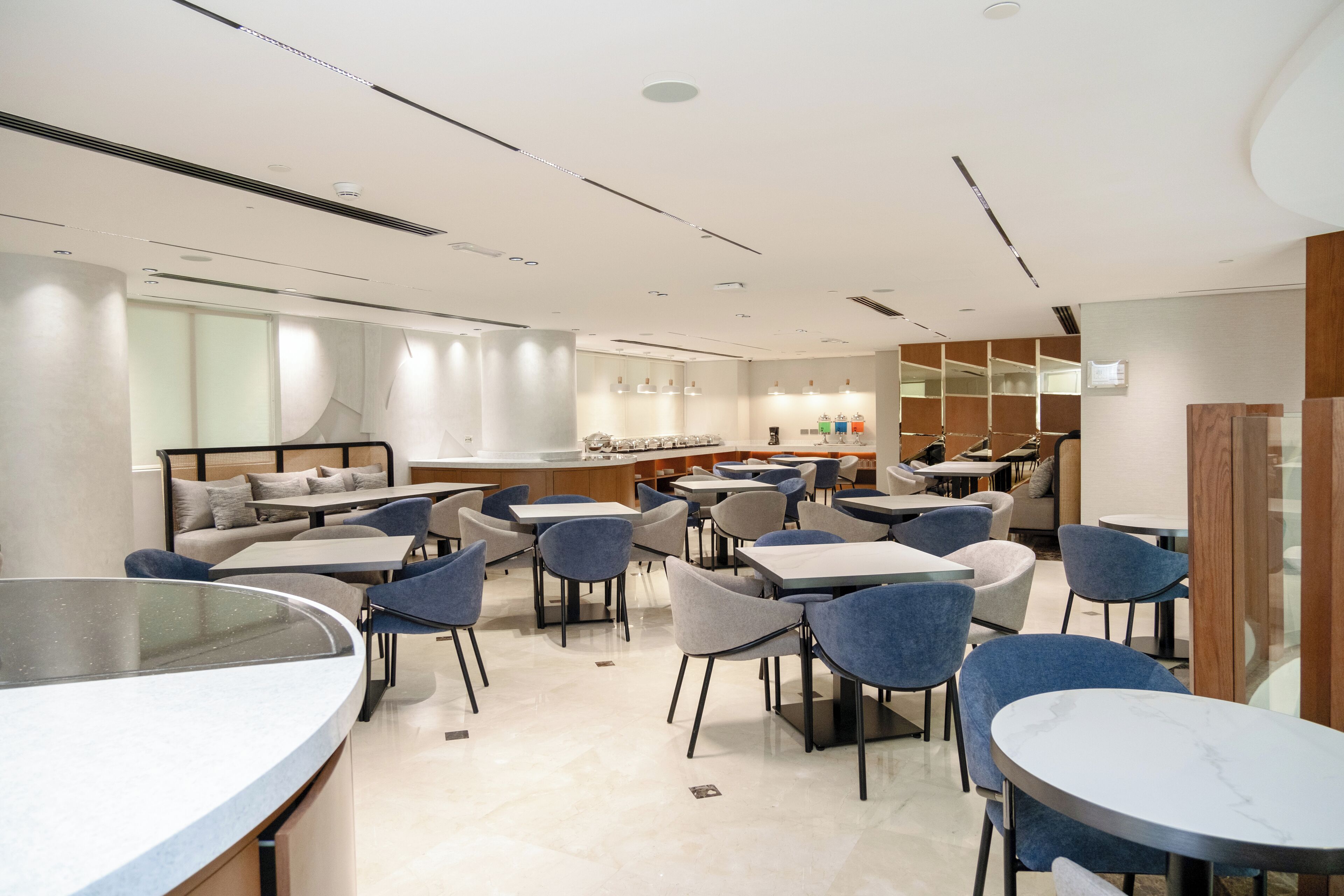 Un restaurant moderne offrant différents types de sièges, notamment des tables rondes et des banquettes, un espace bar et un comptoir avec une vitrine.