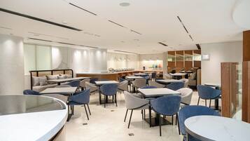 Un restaurant moderne offrant différents types de sièges, notamment des tables rondes et des banquettes, un espace bar et un comptoir avec une vitrine.
