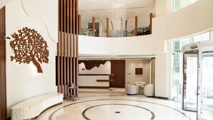 A spacious lobby with a curved bench, a reception desk, and a modern chandelier. - Jannah Executive Hotel Apartments (Abu Dhabi)