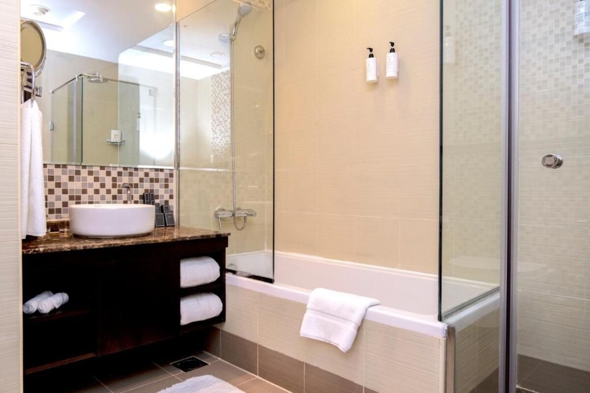 Een moderne badkamer met een douchecabine van glas, een wit wastafelmeubel en een bad.