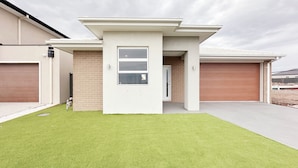 A modern two-story house with a flat roof, a front porch, and a garage. - Jubilee Home/Spacious Bedrooms/Comfy Beds/Smart TV (Manor Lakes)