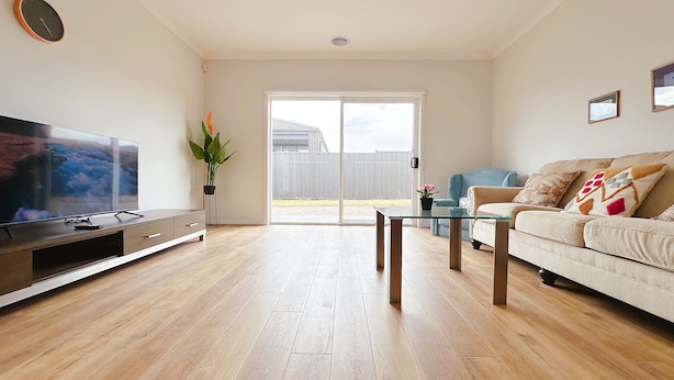 A living room with a flat-screen TV, a glass coffee table, a sofa, and a sliding glass door leading to an outdoor area. - Jubilee Home/Spacious Bedrooms/Comfy Beds/Smart TV (Manor Lakes)