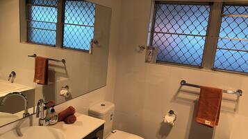 Une salle de bain équipée d’un lavabo, de toilettes et d’un porte-serviettes.