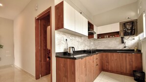 A modern kitchen with wooden cabinets, a marble countertop, and a built-in stove.