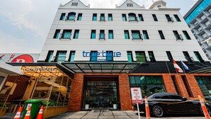 Ein Hotel mit moderner Fassade, einem gut sichtbaren Eingang und einer Beschilderung für Abhol- und Bringservice.
