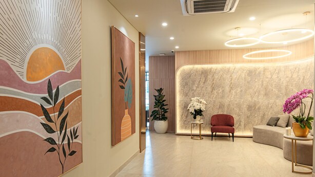 Eine moderne Lobby mit einem Marmor-Rezeptionsschalter, einem roten Sessel und einer großen Topfpflanze.