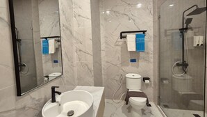 Ein modernes Badezimmer mit Marmorwaschbecken, Toilette und Dusche.