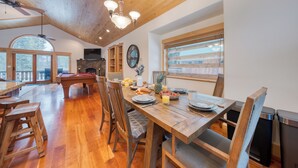 Un comedor amplio con mesas y sillas de madera, una mesa de billar y una chimenea de piedra.
