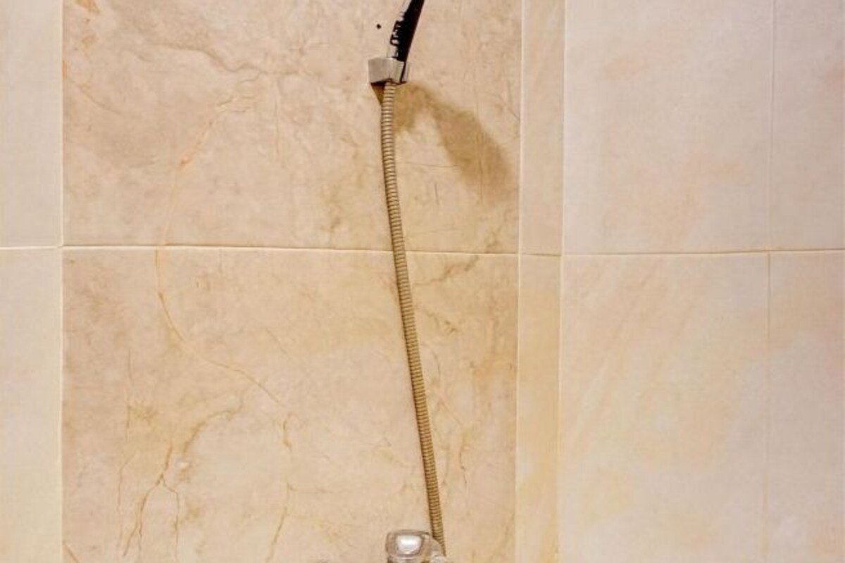 A shower with a hose attached to the wall.