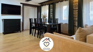 Een moderne woonkamer met een eethoek, houten vloeren, een zwarte televisie, en het logo van Family Apartments Switzerland.