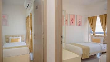 Une chambre d’hôtel avec deux lits, une literie de couleur beige, un grand miroir et des œuvres d’art accrochées aux murs.