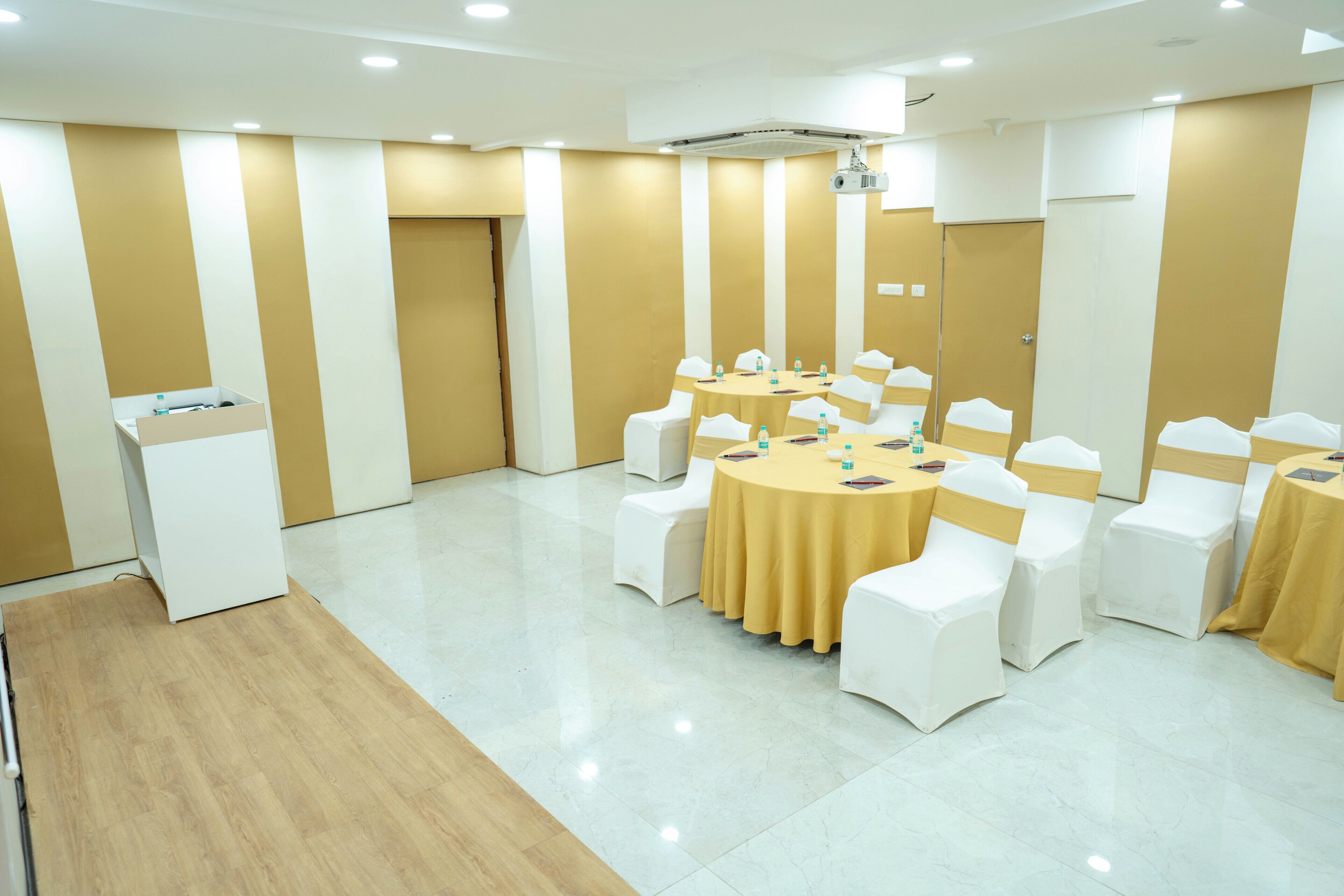 A conference room with a round table, white chairs, and a podium.