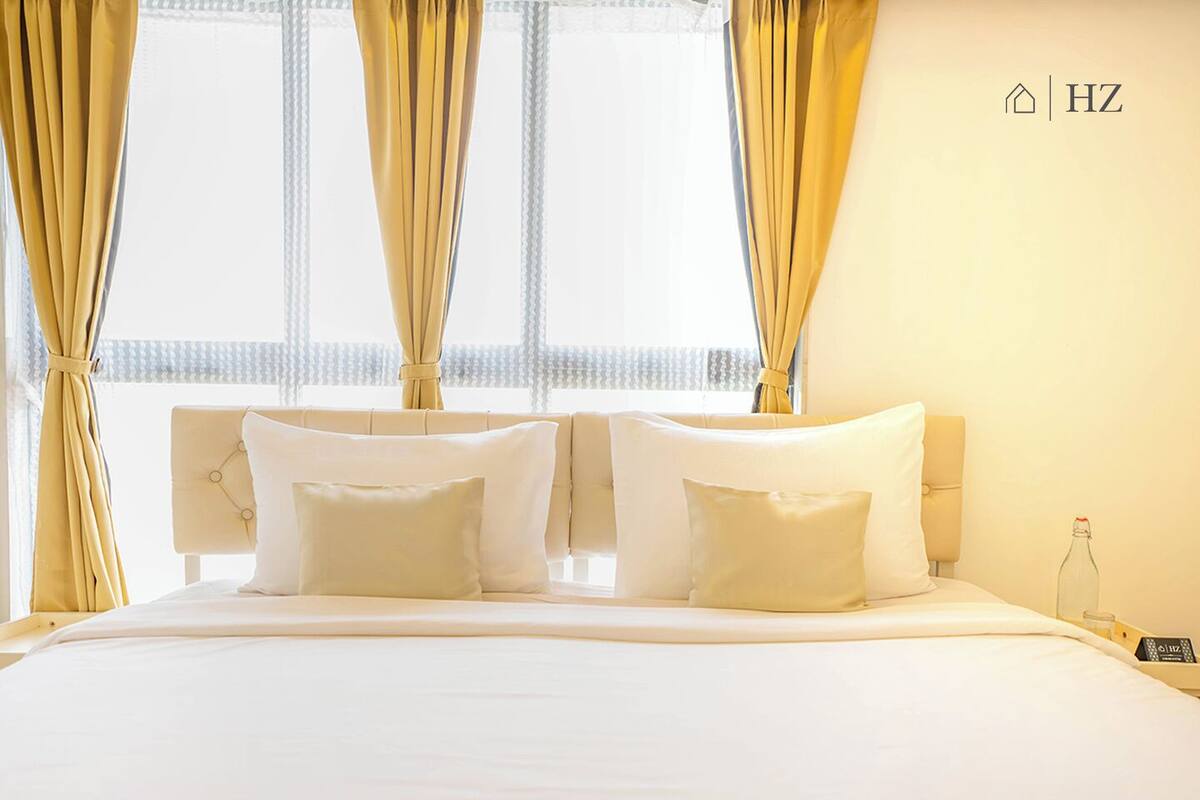 A hotel room with a large bed, two bedside tables, and curtains.