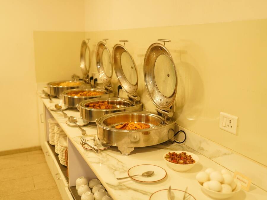A buffet setup with multiple stainless steel bowls containing various dishes, a marble countertop, and a wall socket.
