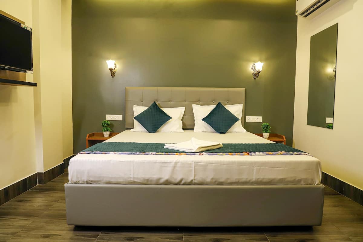 A hotel room with a large bed, two bedside tables, a flat-screen TV, and a mirror on the wall.