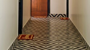 A hallway with a patterned floor, a wooden door labeled "108", and a light fixture on the ceiling. - Arooba Residency Calangute (Calangute)