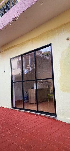 A room with a large sliding glass door leading to an outdoor area with a red brick floor. - Arooba Residency Calangute (Calangute)