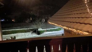 Un espace extérieur enneigé, doté d’une rambarde, d’un sentier recouvert de neige et d’un bâtiment avec un toit en pente.
