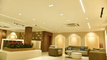 A modern lobby with a reception desk, seating area, and recessed lighting.