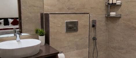 A modern bathroom with a marble wall, a sink, a toilet, a shower, and a mirror.