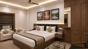 A modern hotel room with a large bed, a glass coffee table, a desk, a chair, and a wardrobe.