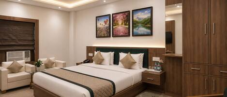 A modern hotel room with a large bed, a glass coffee table, a desk, a chair, and a wardrobe.