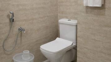 Un baño moderno con inodoro, ducha y un perchero para toallas.