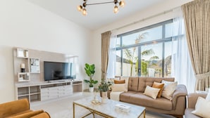 A modern living room with a flat-screen TV, beige sofa, and a coffee table. - Escape to a Modern 3BR Villa w/ a Private Pool & Mountain Views, Al Dana Island (Fujairah)