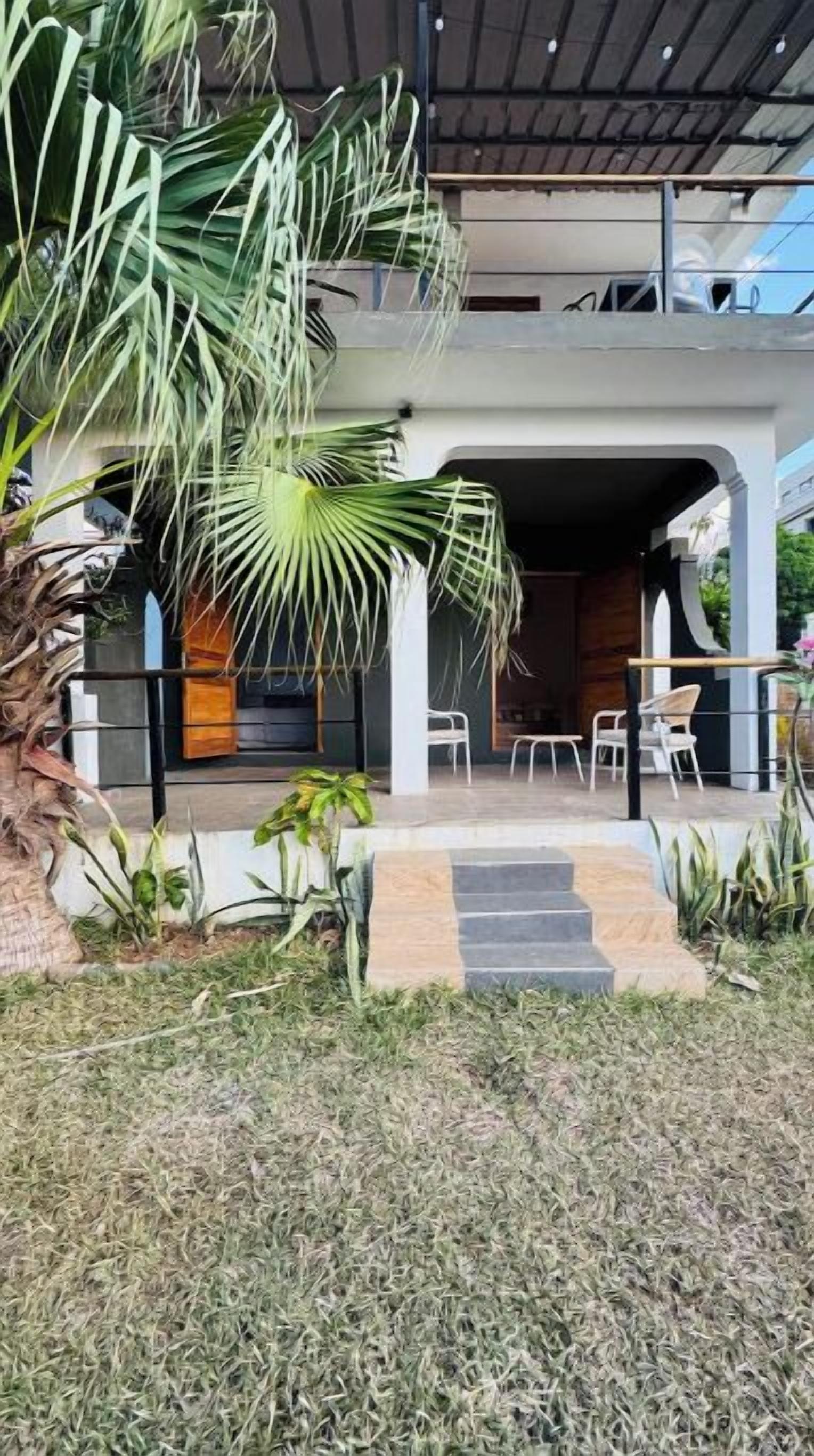 A modern house with a covered outdoor area, steps leading to a door, and outdoor seating.