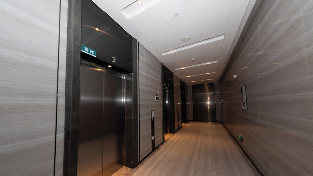 A modern elevator with a digital display, a hallway with a wooden floor, and a wall with a textured pattern.